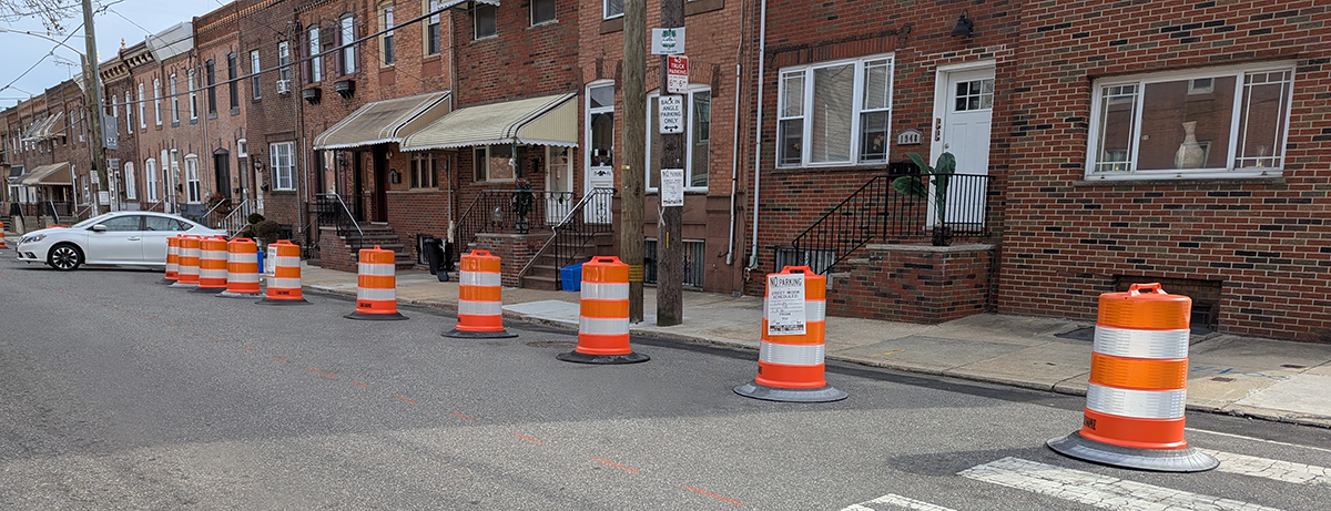 Picture of plastic drums blocking spots that are usually parking spots.